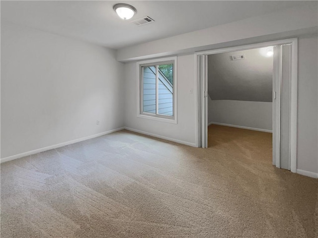 carpeted spare room with vaulted ceiling