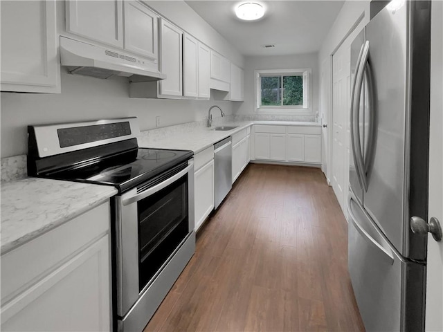 kitchen with light stone countertops, dark hardwood / wood-style floors, stainless steel appliances, white cabinetry, and sink