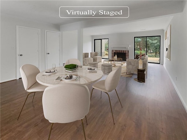 dining space featuring a brick fireplace and dark hardwood / wood-style floors