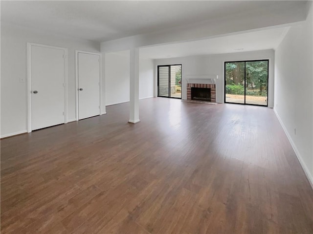 unfurnished living room featuring a brick fireplace and dark hardwood / wood-style flooring