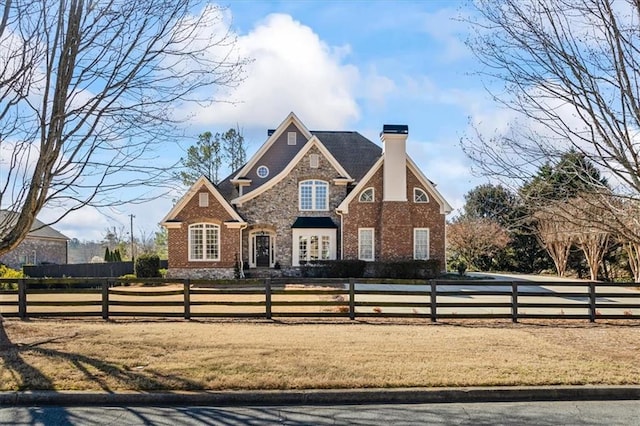 view of front of home featuring a fenced front yard, stone siding, and a chimney