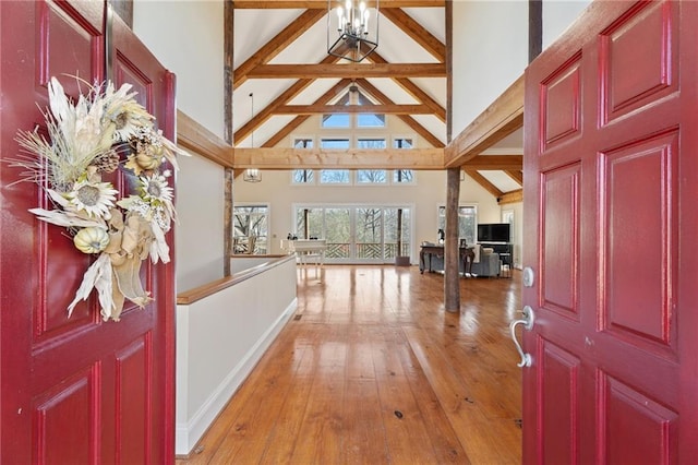 foyer featuring high vaulted ceiling, beam ceiling, light wood-type flooring, and a chandelier