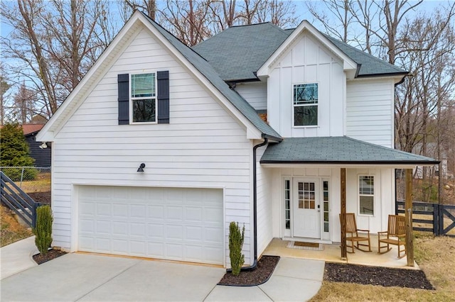 view of front of property featuring an attached garage, a shingled roof, fence, and board and batten siding