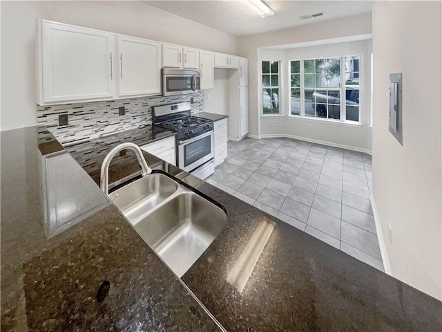 kitchen featuring tasteful backsplash, light tile patterned flooring, white cabinets, and appliances with stainless steel finishes