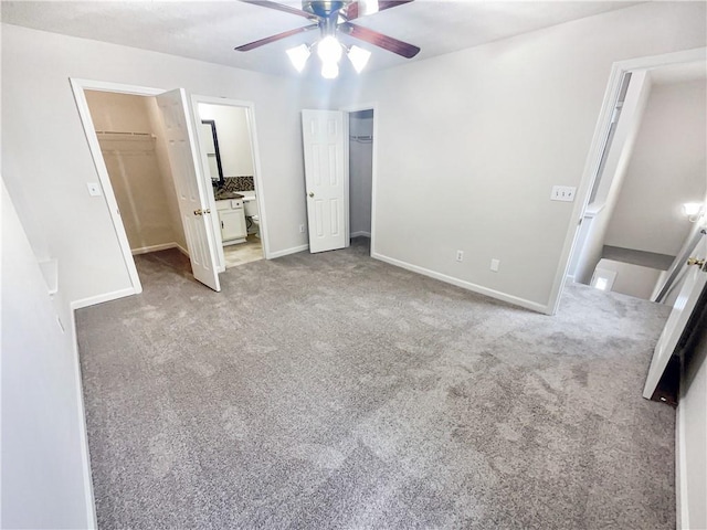 unfurnished bedroom featuring connected bathroom, a spacious closet, carpet floors, a closet, and ceiling fan