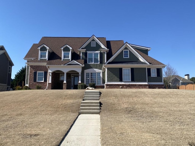 view of front of home featuring a porch, brick siding, and a shingled roof