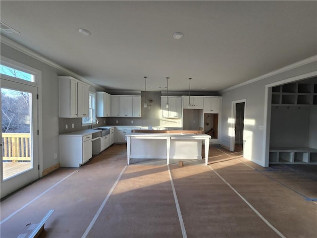 kitchen featuring pendant lighting, tasteful backsplash, sink, white cabinets, and a center island