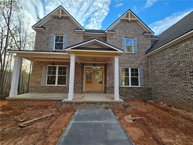 view of exterior entry featuring french doors and a porch