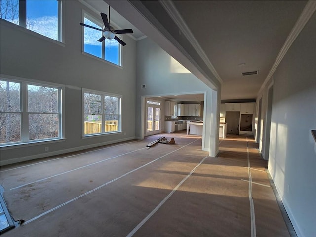 interior space with ornamental molding, concrete floors, and a high ceiling