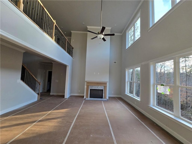 unfurnished living room featuring a high ceiling, crown molding, plenty of natural light, and a fireplace