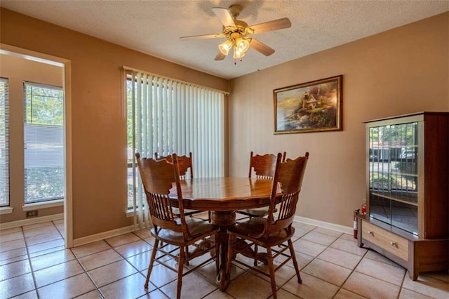 dining room with ceiling fan, a wealth of natural light, light tile patterned flooring, and a textured ceiling