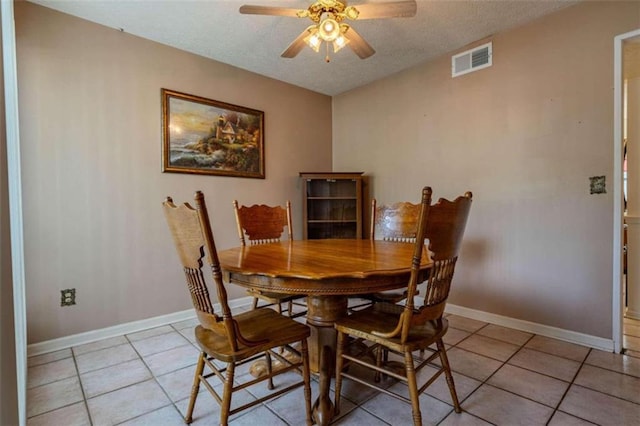 tiled dining area with a textured ceiling and ceiling fan