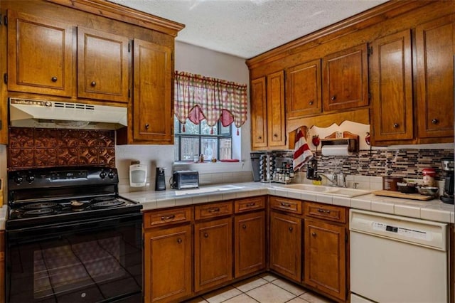 kitchen featuring dishwasher, light tile patterned floors, tile counters, sink, and black range with electric cooktop