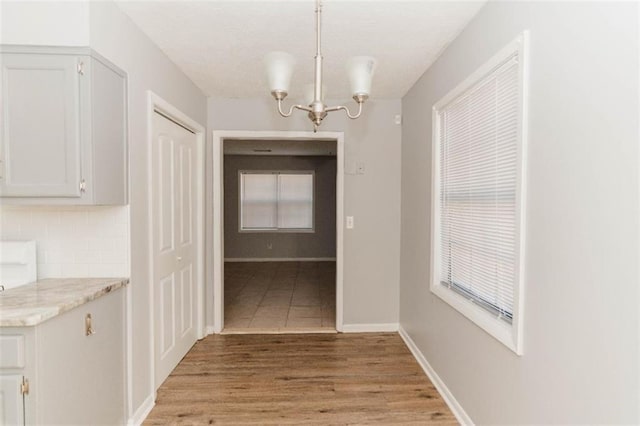 unfurnished dining area with an inviting chandelier and light wood-type flooring