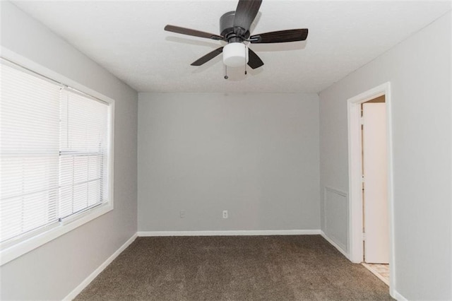 spare room featuring dark colored carpet and ceiling fan