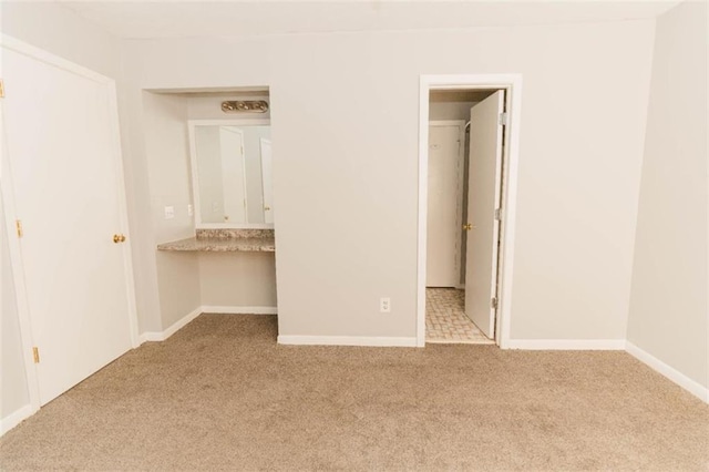 unfurnished bedroom featuring light carpet, a closet, and built in desk