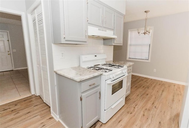 kitchen featuring pendant lighting, light hardwood / wood-style floors, white range, and a notable chandelier