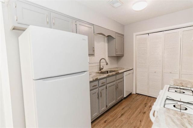 kitchen with gray cabinets, sink, white appliances, and light hardwood / wood-style flooring