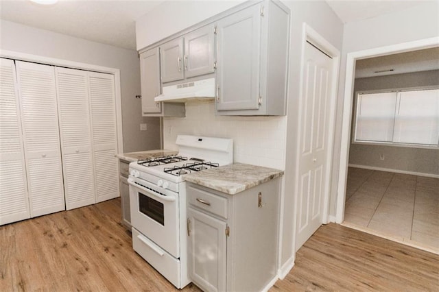 kitchen featuring white range with gas stovetop, decorative backsplash, and light hardwood / wood-style floors