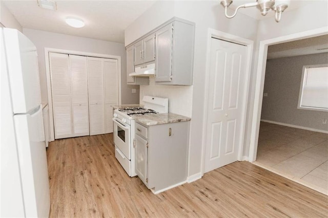 kitchen with light hardwood / wood-style floors, white appliances, and a chandelier