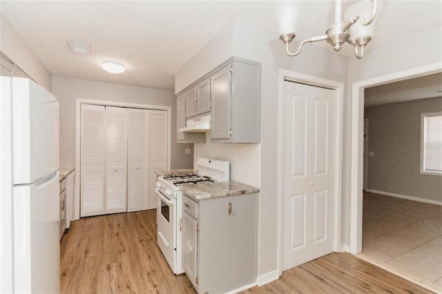 kitchen featuring light hardwood / wood-style floors, white appliances, and an inviting chandelier