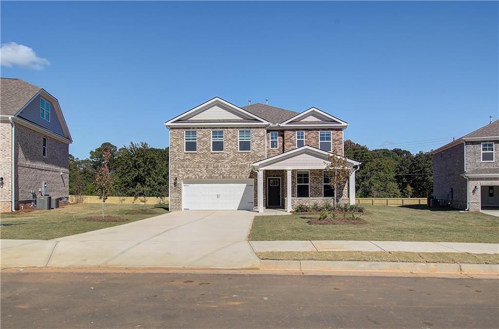 view of front of property featuring central AC, a garage, and a front lawn