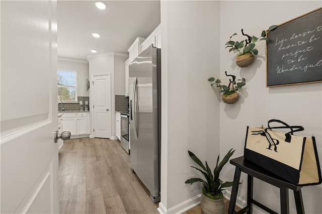 corridor with sink, ornamental molding, and light hardwood / wood-style flooring