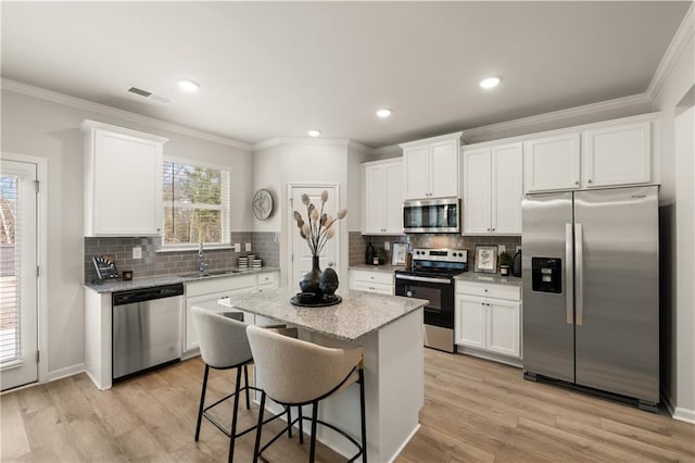 kitchen featuring a center island, a kitchen bar, white cabinetry, stainless steel appliances, and sink