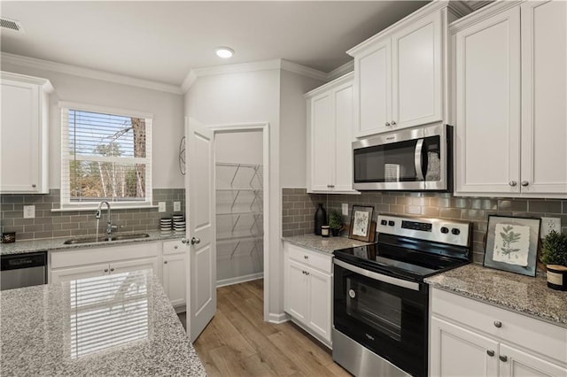 kitchen with stainless steel appliances, light wood-type flooring, light stone countertops, white cabinets, and sink