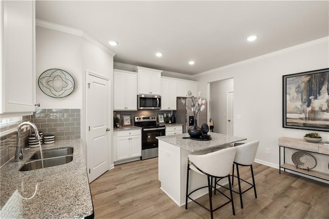 kitchen with a kitchen island, sink, light stone countertops, stainless steel appliances, and white cabinets