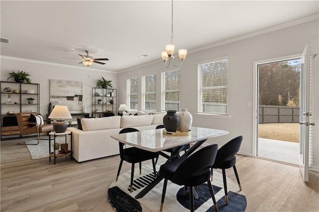 dining room with light hardwood / wood-style floors, ornamental molding, and ceiling fan with notable chandelier