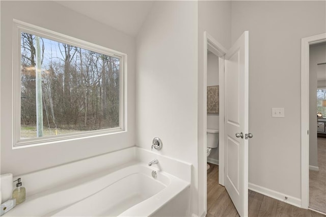 bathroom with a tub, hardwood / wood-style flooring, a wealth of natural light, and toilet