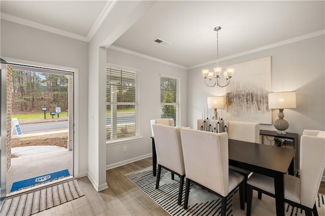 dining area with light wood-type flooring, a chandelier, and ornamental molding