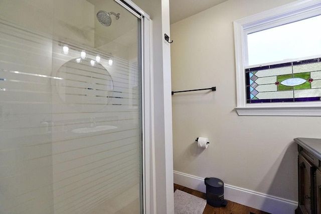 full bath with vanity, a stall shower, and baseboards