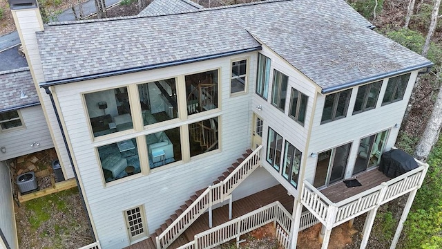 exterior space featuring stairs, a chimney, cooling unit, and roof with shingles