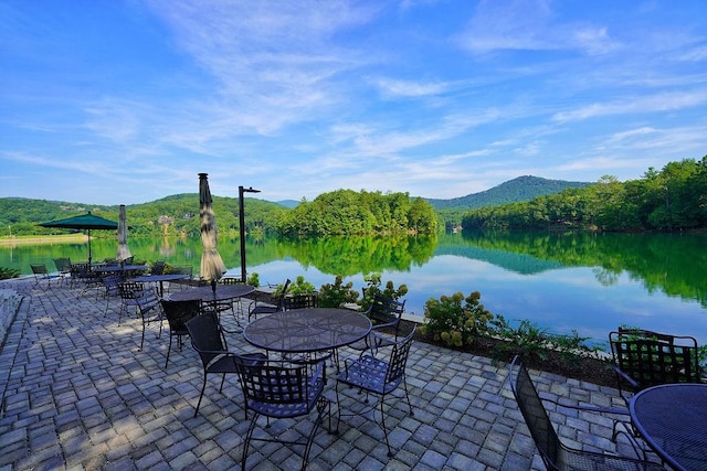 view of patio with a water and mountain view and outdoor dining area