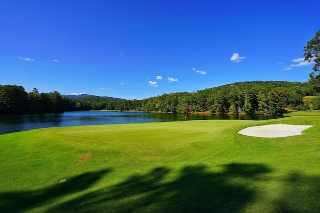view of home's community featuring view of golf course, a wooded view, a water view, and a yard