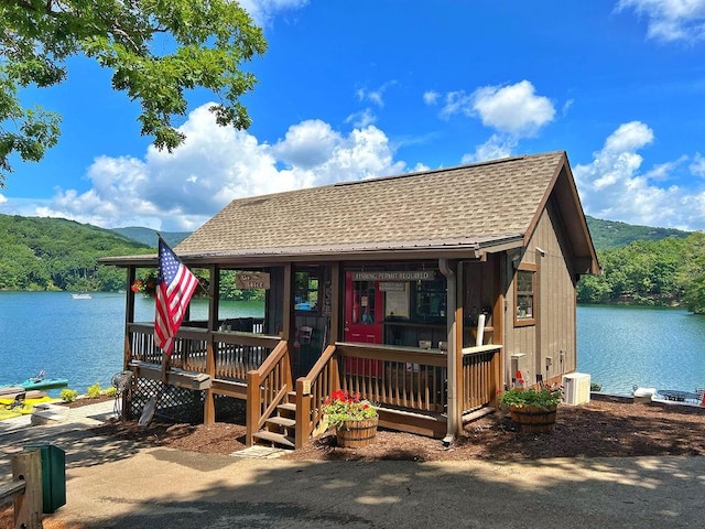 chalet / cabin with a water and mountain view and a shingled roof