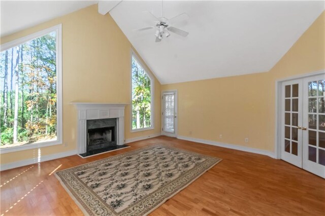 living room featuring french doors, hardwood / wood-style floors, a high end fireplace, ceiling fan, and beamed ceiling