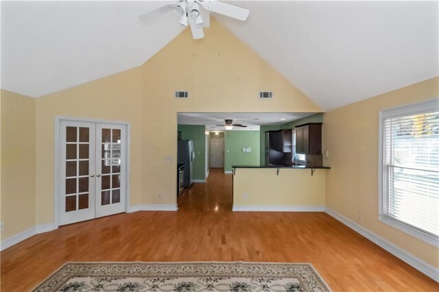 unfurnished living room featuring ceiling fan, light hardwood / wood-style flooring, and french doors