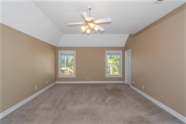 carpeted empty room featuring ceiling fan, vaulted ceiling, and a healthy amount of sunlight