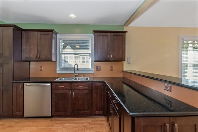 kitchen with dishwasher, dark stone countertops, kitchen peninsula, sink, and light hardwood / wood-style flooring