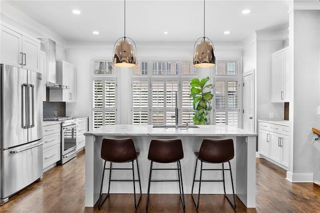 kitchen with stainless steel appliances, an island with sink, hanging light fixtures, and white cabinets