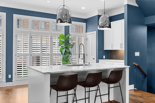 kitchen featuring pendant lighting, sink, tasteful backsplash, and white cabinets