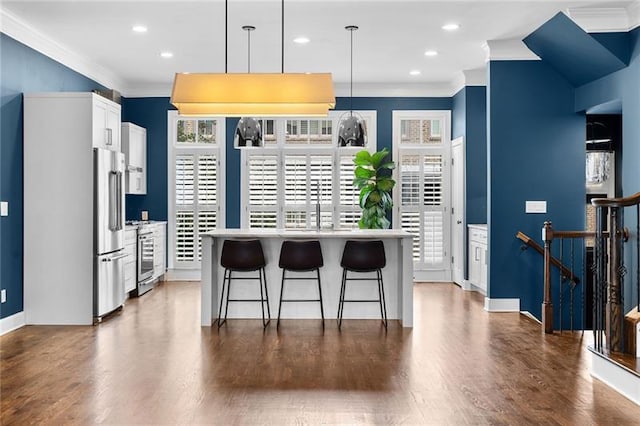 kitchen with decorative light fixtures, white cabinetry, a kitchen breakfast bar, ornamental molding, and stainless steel appliances