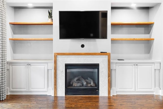 unfurnished living room with dark hardwood / wood-style flooring, a fireplace, and built in shelves