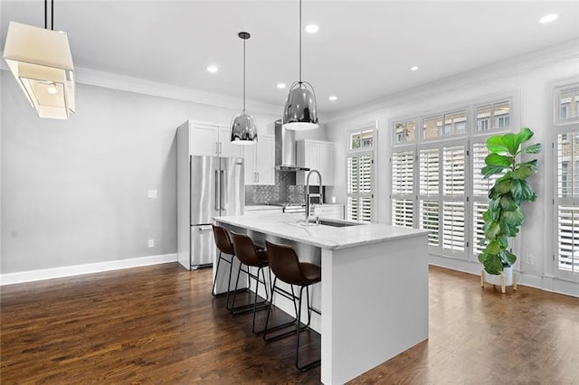 kitchen with hanging light fixtures, high quality fridge, sink, and white cabinets