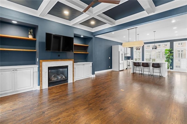 unfurnished living room featuring crown molding, built in shelves, coffered ceiling, and a premium fireplace