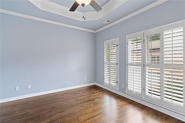 empty room featuring crown molding, dark wood-type flooring, ceiling fan, and a tray ceiling