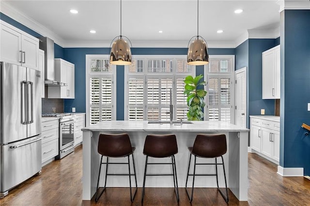 kitchen with wall chimney exhaust hood, a healthy amount of sunlight, stainless steel appliances, and a center island with sink